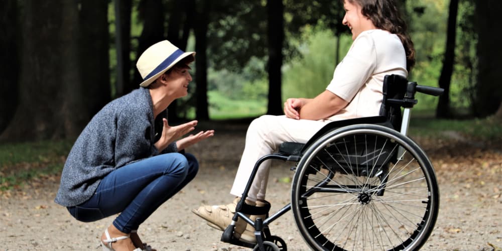 young woman talking to woman on a wheelchair and smiling