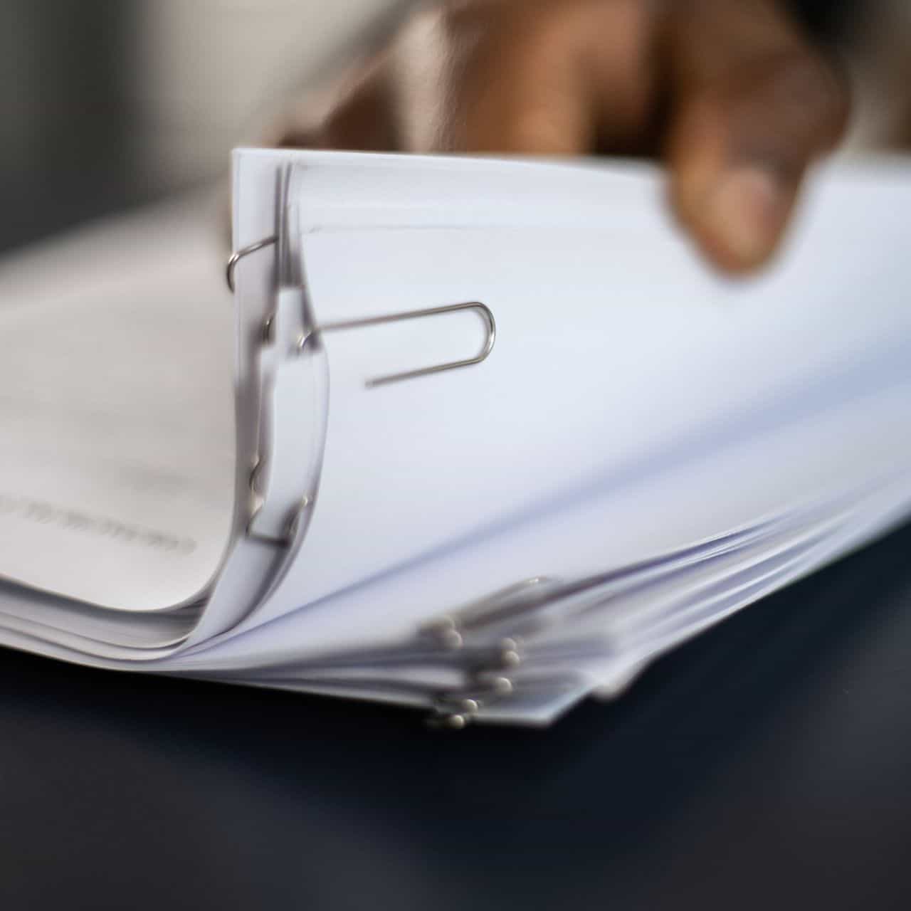 a stack of documents with a person sorting through them