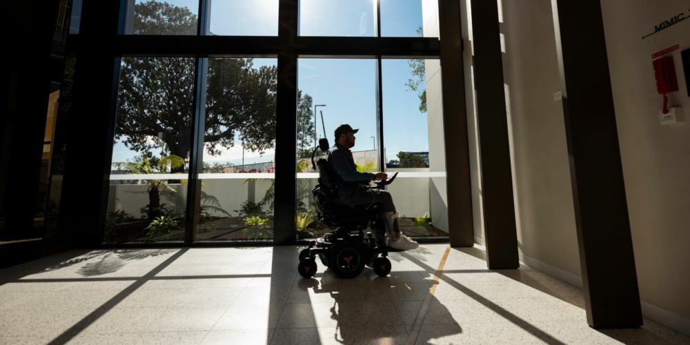 image of a man in wheelchair infront of large glass windows