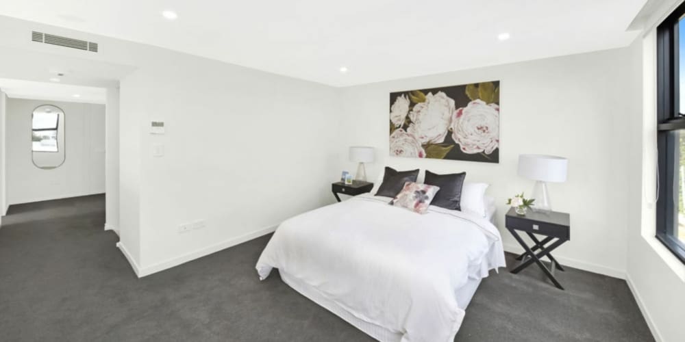 the grace apartments bedroom with grey carpet and white bedding