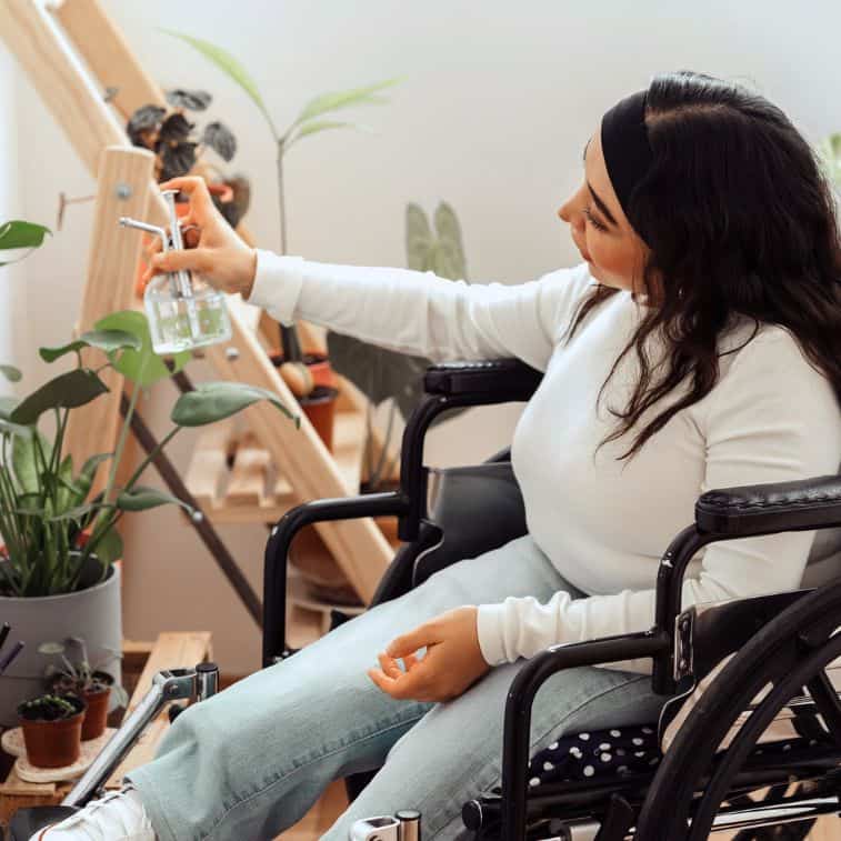 woman in a wheelchair watering plants at home