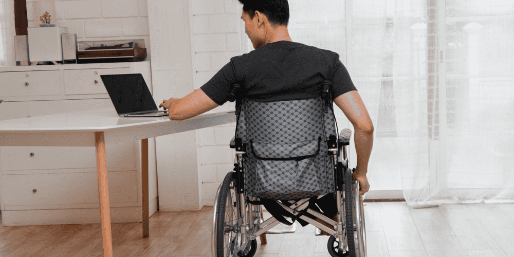 man in a wheelchair looking at his laptop